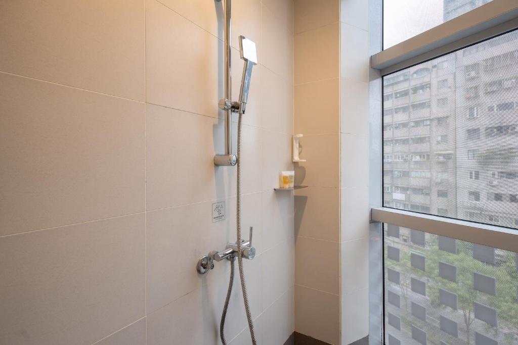 a shower stall in a bathroom with a window at CHECK inn Taipei Xinyi in Taipei