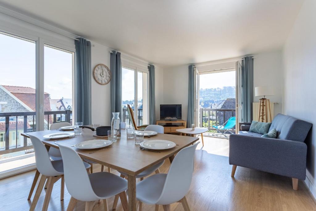 een eetkamer met een tafel en stoelen en een bank bij Le Carrousel - Appartement avec studio attenant in Deauville