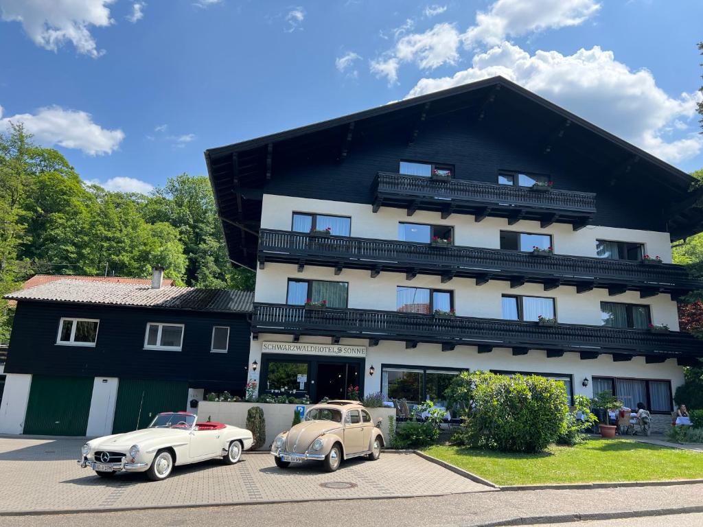 dos coches viejos estacionados frente a un edificio en Schwarzwaldhotel Sonne en Baden-Baden