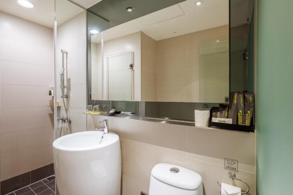 a bathroom with a toilet and a sink and a mirror at CHECK inn Taipei Xinyi in Taipei