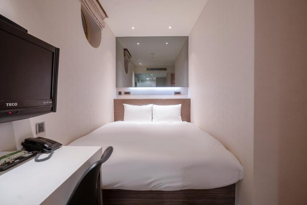 a hotel room with a bed and a television at CHECK inn Taipei Xinyi in Taipei