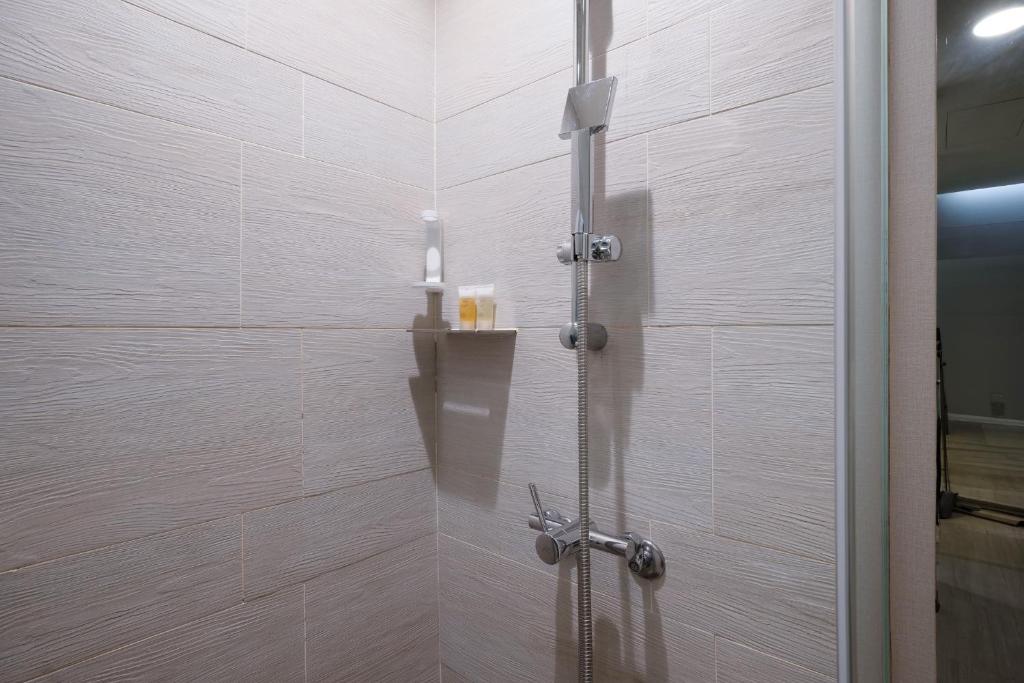 a shower in a bathroom with white tiles at CHECK inn Taipei Xinyi in Taipei