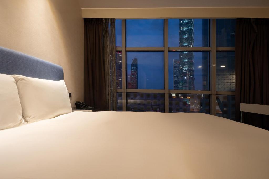 a bedroom with a large white bed and a window at CHECK inn Taipei Xinyi in Taipei