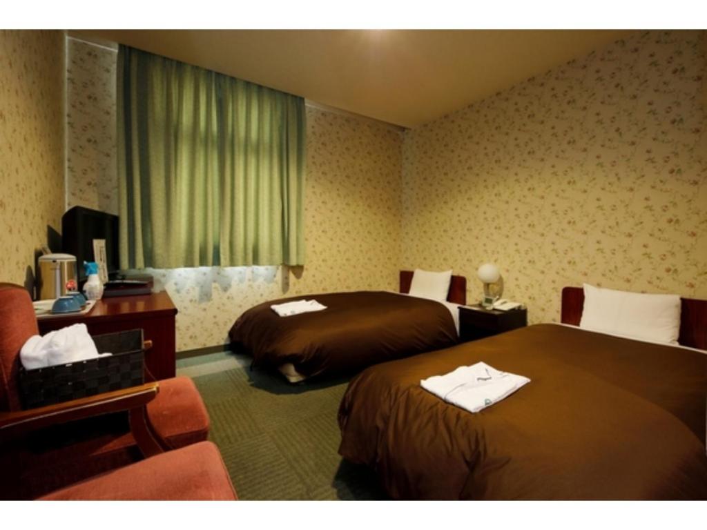 a hotel room with two beds and a chair at Zentsuji Grand Hotel - Vacation STAY 16635v in Zentsuji