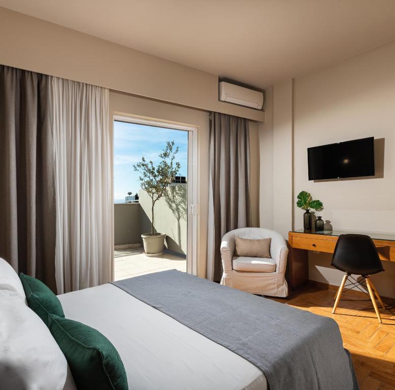 a hotel room with a bed and a chair and a window at Hotel Delfini in Piraeus