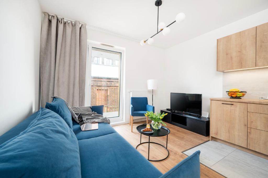 un salon avec un canapé bleu et une télévision dans l'établissement Komfortowe Apartamenty z Garażem na Milionowej, à Łódź