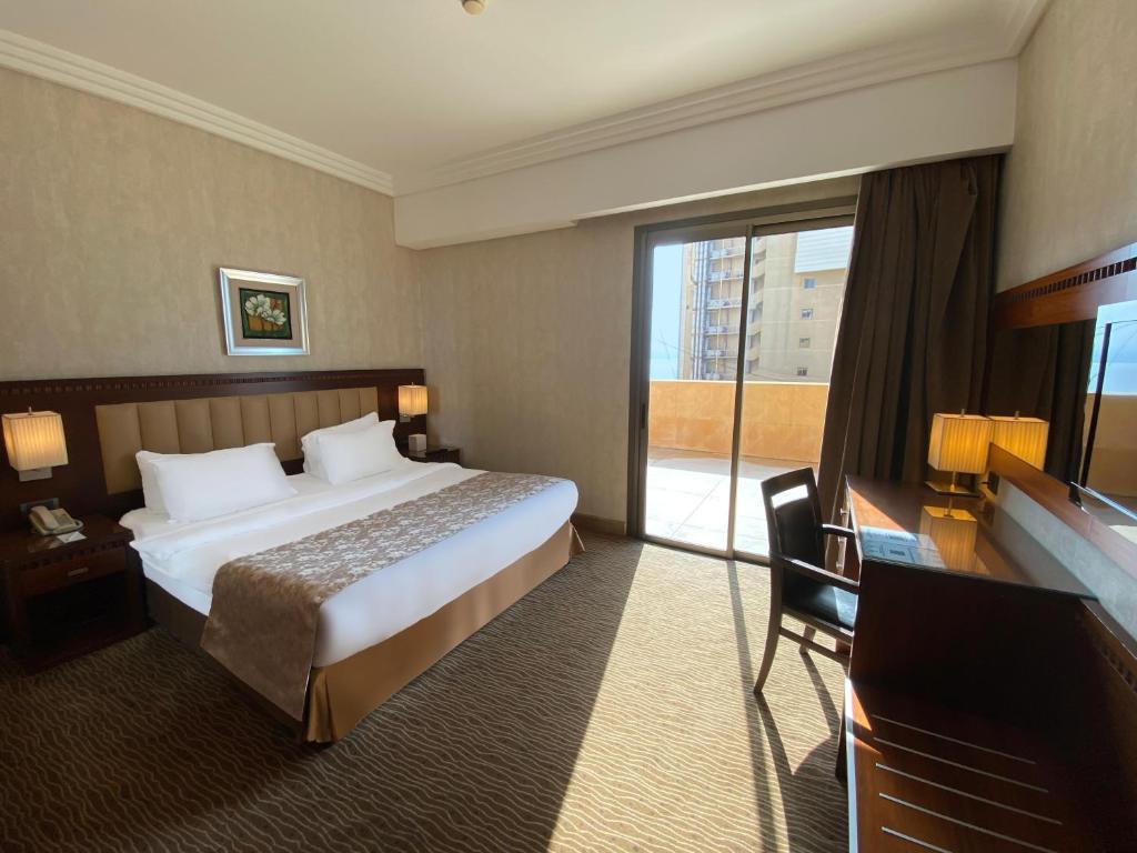 a hotel room with a bed and a large window at Lancaster Suites Raouche in Beirut