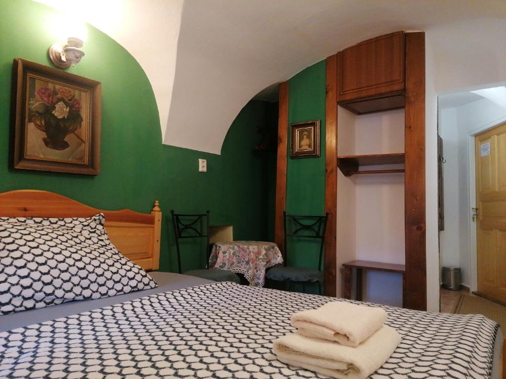 a bedroom with green walls and a bed with two towels at Guest House Olšakovský in Český Krumlov