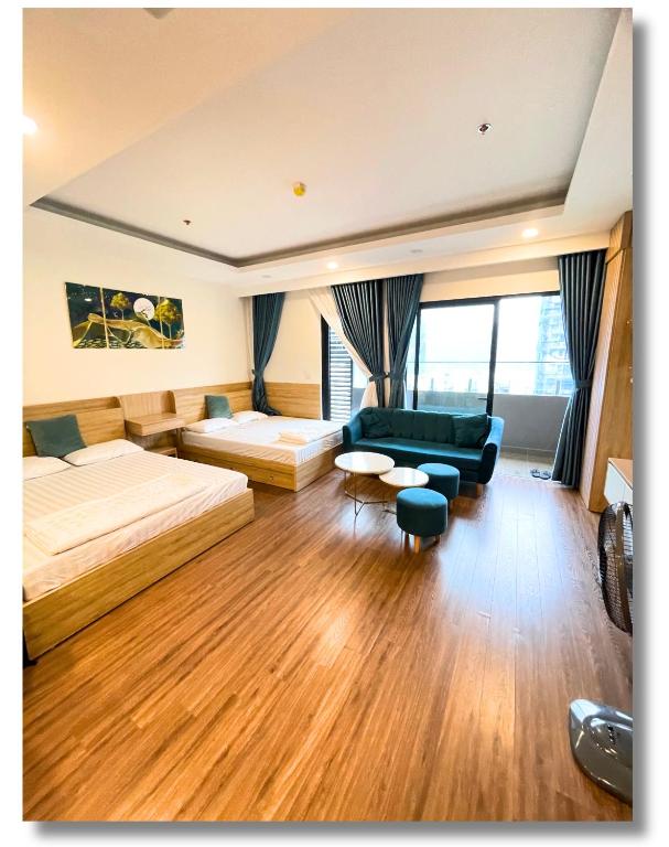 a bedroom with two beds and a couch and a table at FLC Luxury Apartment Quy Nhon in Quy Nhon