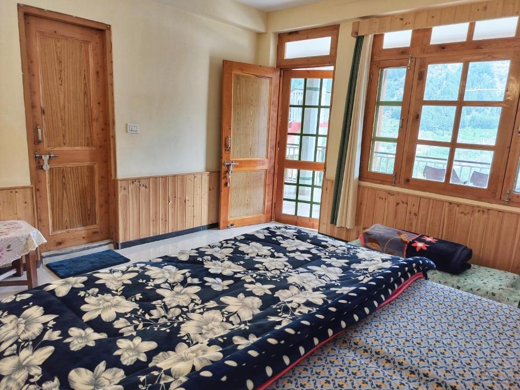 een slaapkamer met een groot bed in een kamer met ramen bij MyTribe Homestay in Manāli