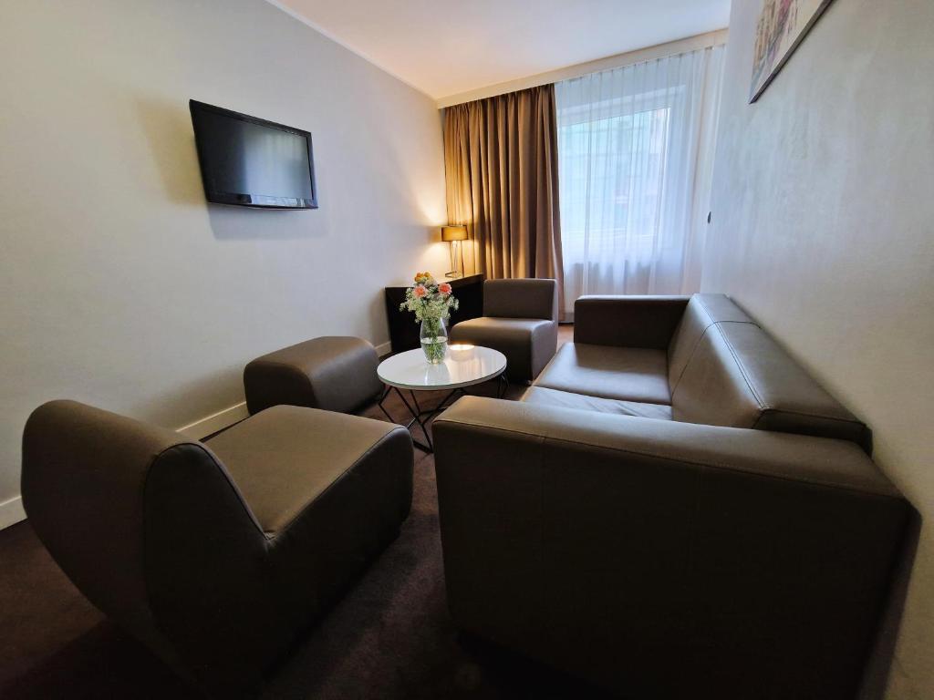 a hotel room with a couch and chairs and a table at Platinum Apartments Aparthotel in Poznań