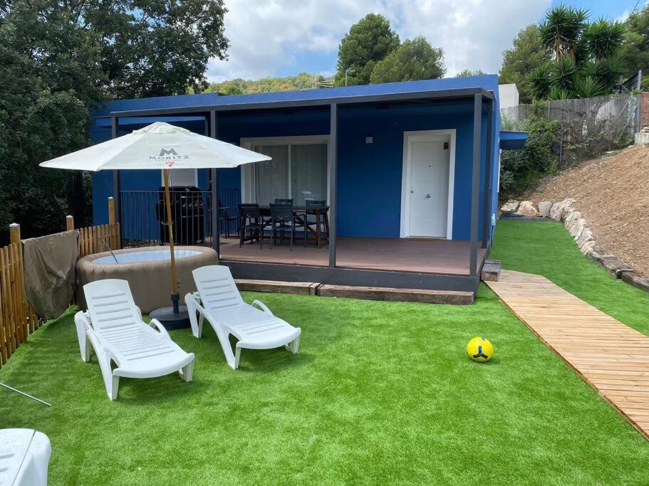 a small blue house with chairs and an umbrella at La Casa Azul in Maspujols