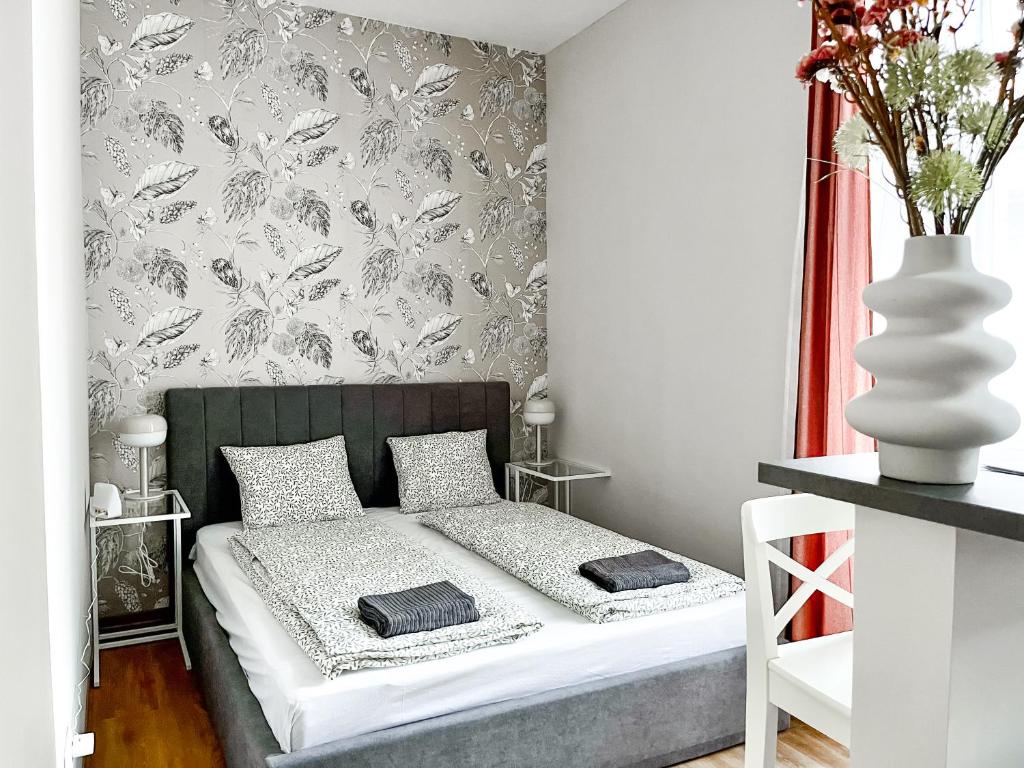 a small bedroom with a bed and a wall with wallpaper at T32 Central Modern Suites in Budapest