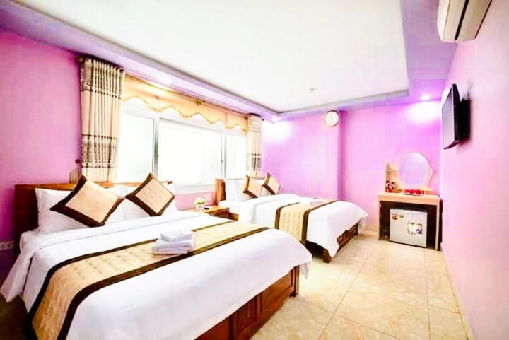 a room with three beds with pink walls at Pink Boutique Inn - Hotel Elite in Cat Ba