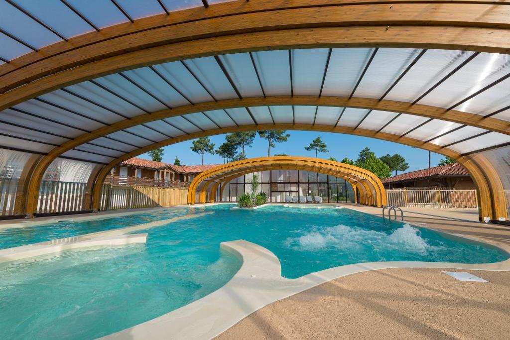 an indoor swimming pool with an arched ceiling at Les Cottages Du Lac in Parentis-en-Born