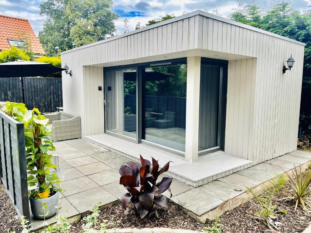 un pequeño cobertizo blanco con puertas de cristal en un patio en East Bridgford Summerhouse Inc Spa and Treatments, en East Bridgford