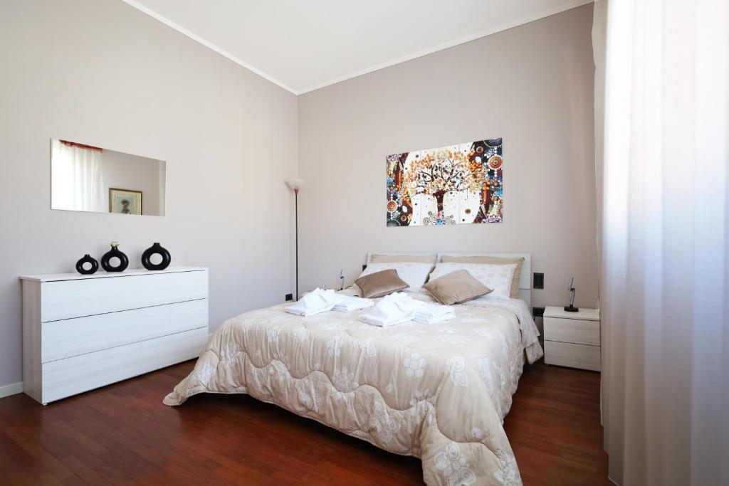 a white bedroom with a bed and a painting on the wall at La casa di Jacopo [Intero appartamento+parcheggio] in Pistoia