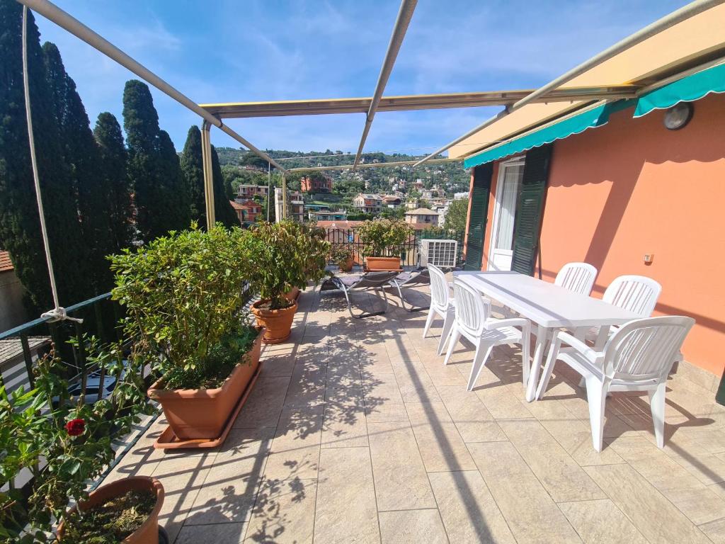 um pátio com uma mesa branca, cadeiras e plantas em Turchino Apartment & Terrazza della Luisa by PortofinoVacanze em Santa Margherita Ligure