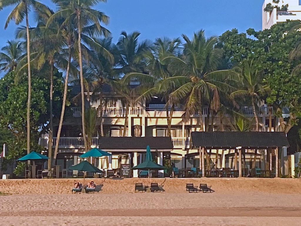 a hotel on the beach with people sitting under umbrellas at Suite Lanka in Hikkaduwa