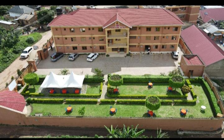 PRIMEROSE HOTEL في Mubende: نموذج منزل مع حديقة ومبنى