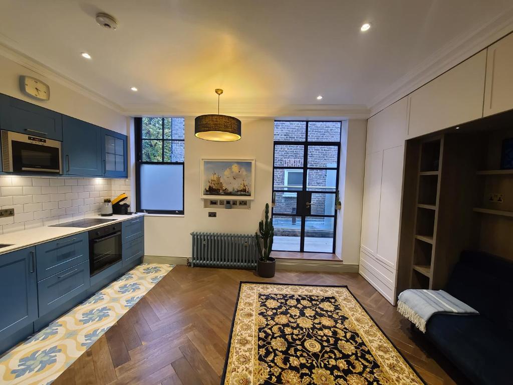 a kitchen with blue cabinets and a couch in a room at Boutique Linden Gardens 1st floor and loft apartments in London