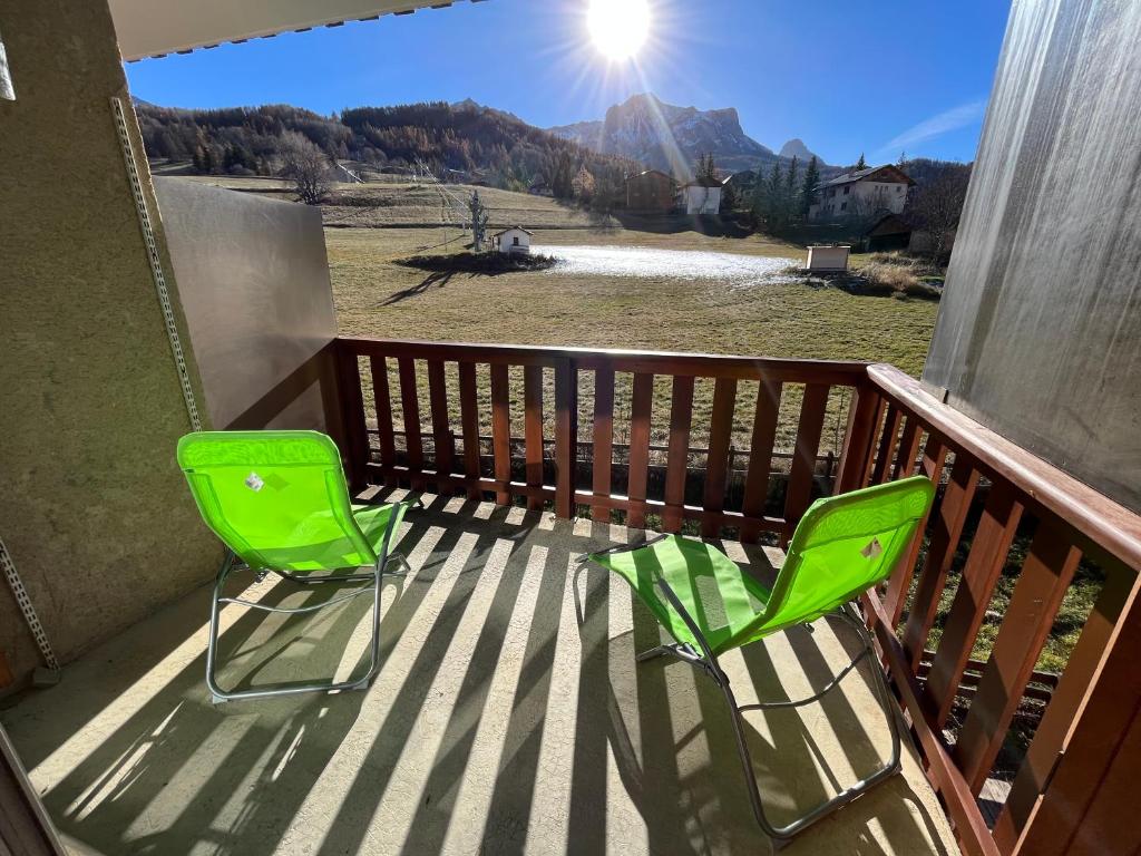 duas cadeiras verdes num deque com vista para uma montanha em Les Sources appartement T2 em Enchastrayes