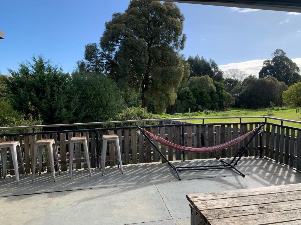 a hammock on a deck with a fence and trees at Bairnsdale Workers Accommodation in Lucknow