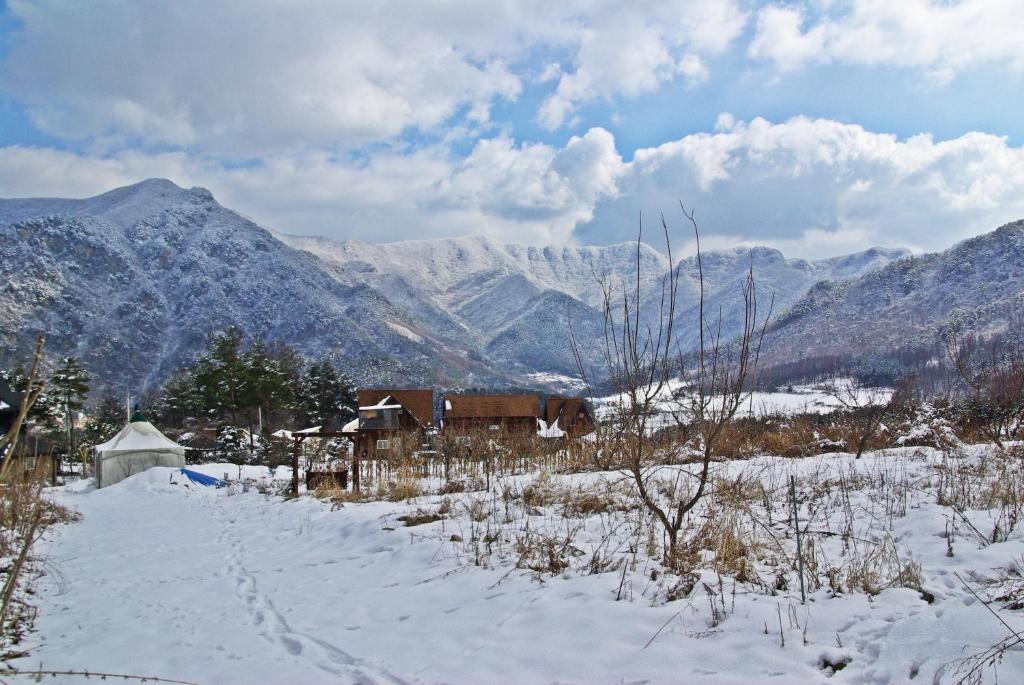 a house in the snow with mountains in the background at Cabin Liun in Pyeongchang