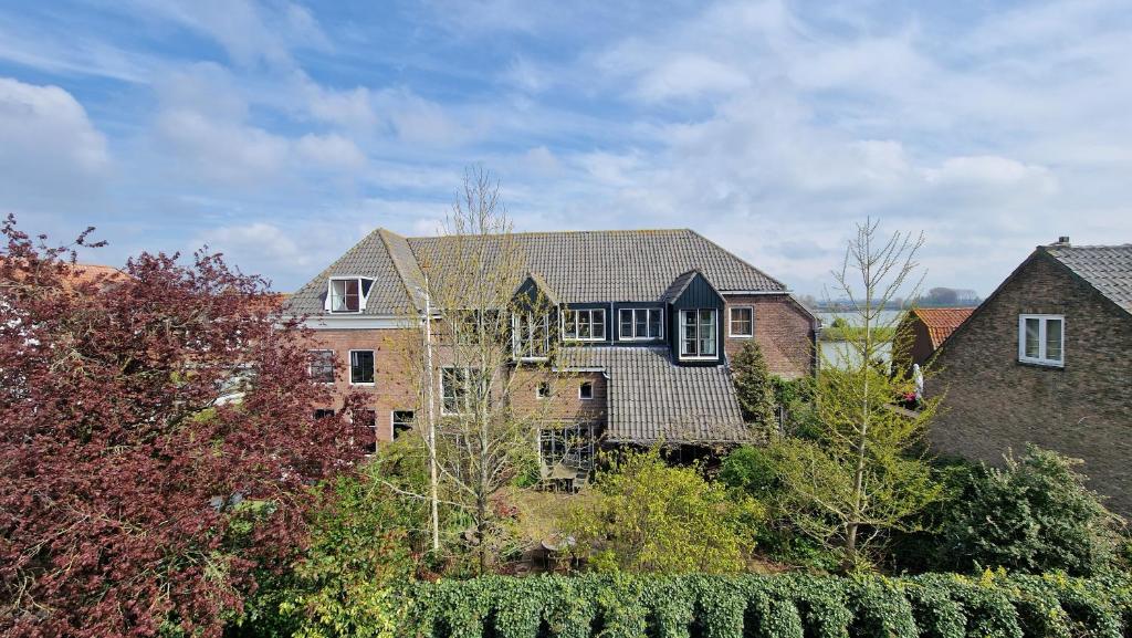a large brick house with a roof at Waar Maas & Waal..... in Woudrichem