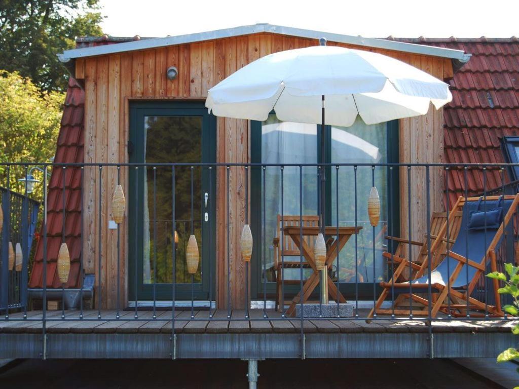 una casa con sillas y una sombrilla en una terraza en Ferien am Roten Haus, en Buckow