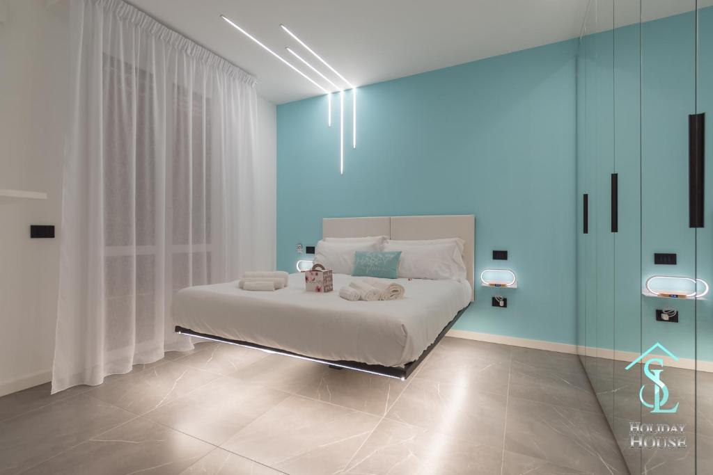 a bedroom with a white bed with blue walls at Tiffany - SL Holiday House in Desenzano del Garda