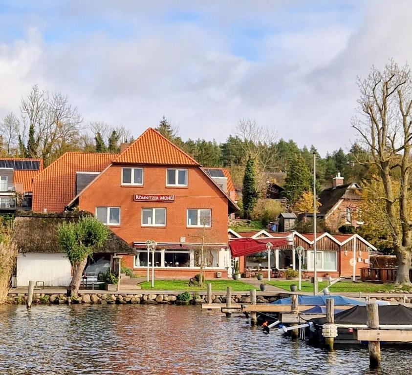 a house with a dock next to a body of water at Hotel am See Römnitzer Mühle in Römnitz