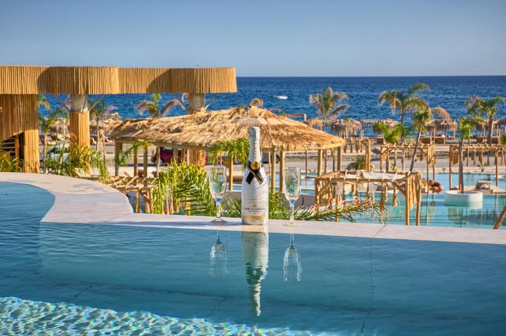 una piscina in un resort con una persona che porta un bicchiere di vino di Alia Luxury Beachfront Suites and SPA a Haraki
