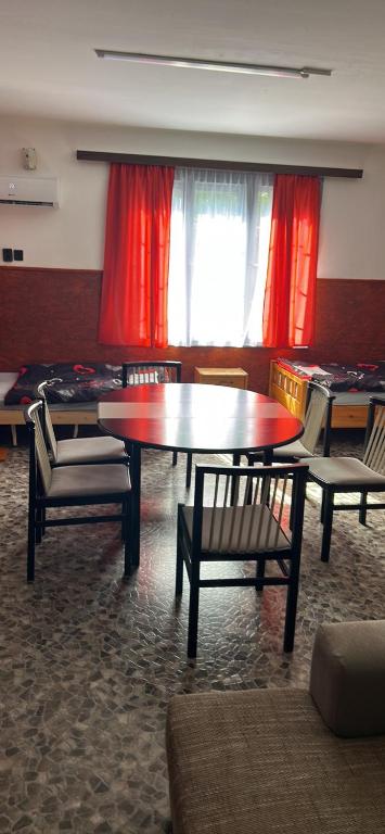 a table and chairs in a room with red curtains at Lala-Lak in Kisújszállás
