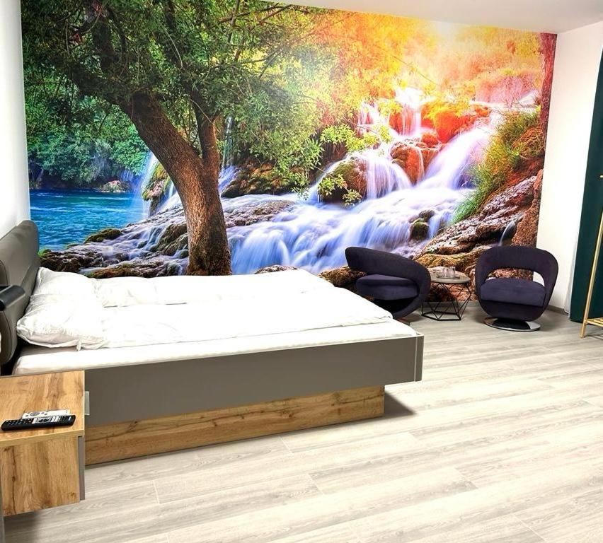 ein Wasserfall-Wandbild in einem Zimmer mit einem Bett in der Unterkunft Weißes Haus in Plauen