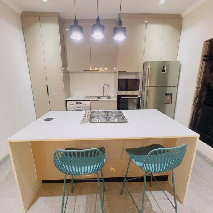 a kitchen with two blue chairs and a counter top at Cosy 2 bed house w power backup in Sandton