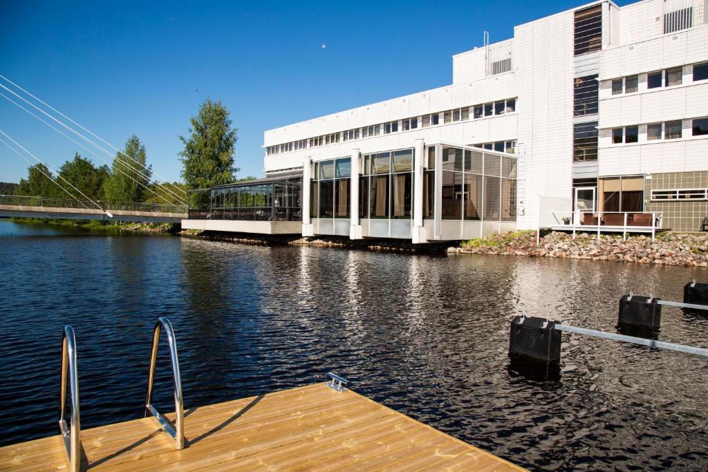 a building next to a body of water with a dock at Finlandia Hotel Alba in Jyv&auml;skyl&auml;