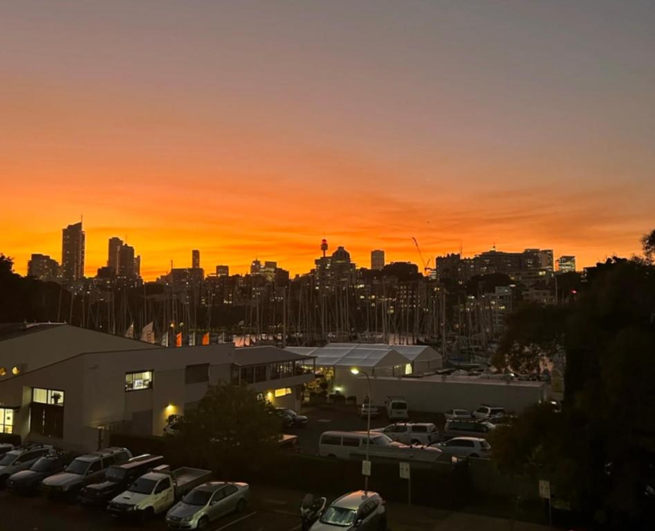 a city skyline at sunset with cars parked in a parking lot at 2 Story Apartment with Harbour Views in Sydney