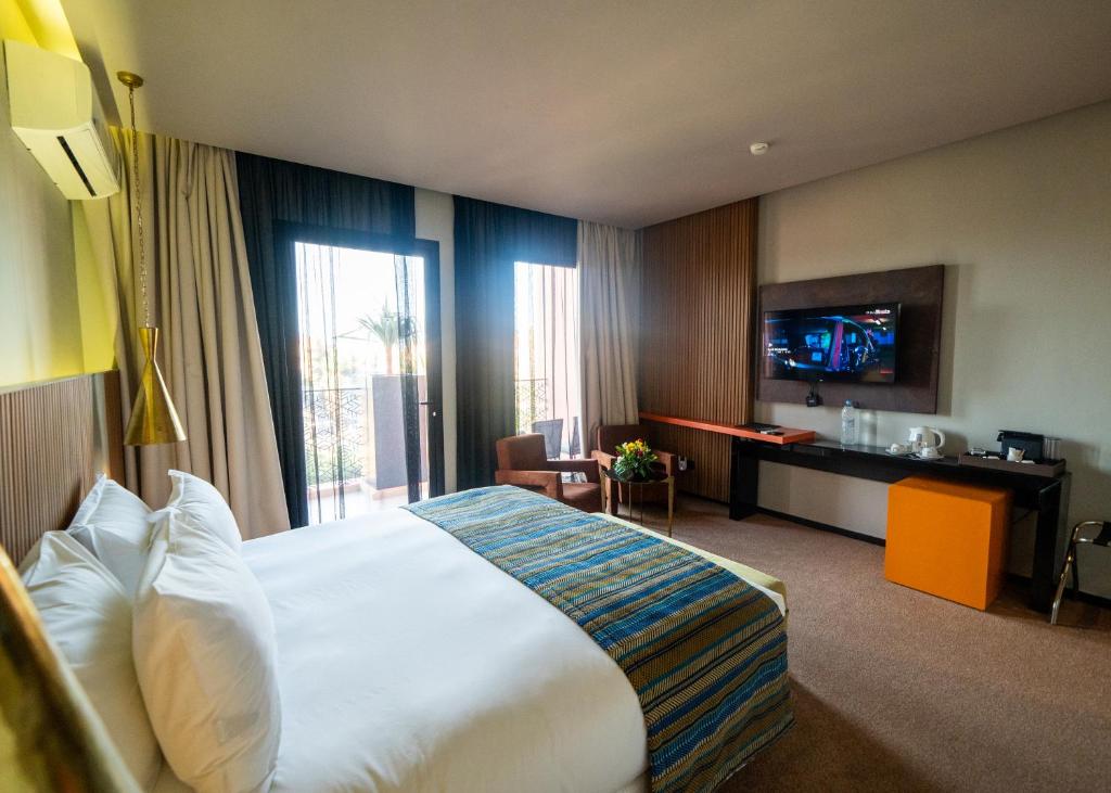 Habitación de hotel con cama grande y TV en Hotel Le Rocher Marrakech, en Marrakech