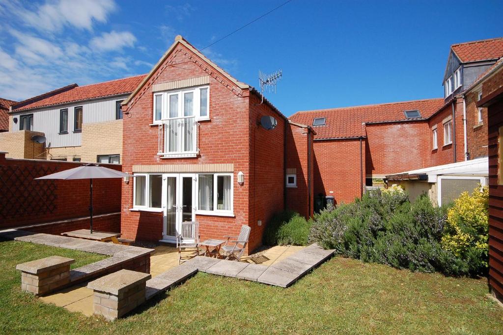 a brick house with a patio in the yard at 2 Old Dairy Court in Sheringham