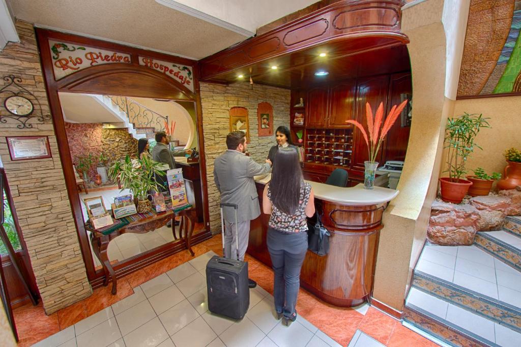 un hombre y una mujer parados en un mostrador en una tienda en Hotel Rio Piedra, en Cuenca