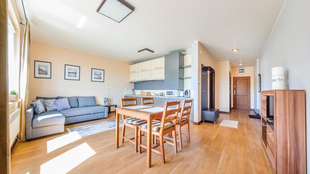 een keuken en een woonkamer met een tafel en stoelen bij Apartamenty Sun & Snow Niska 10 in Krynica Morska