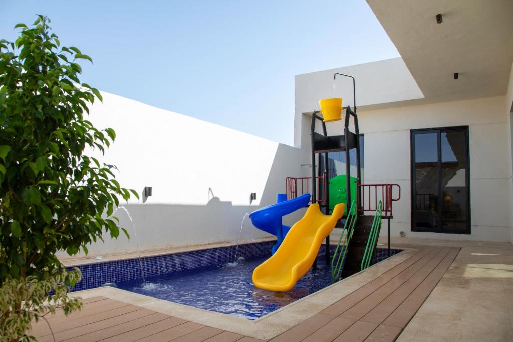 a pool with a playground with a slide at المرفأ 2 شاليه مع مسبح والعاب مائية وغرف نوم فاخرة in Khalij Salman