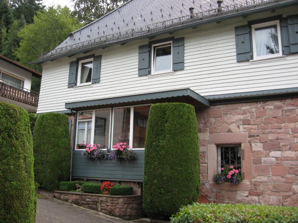 uma casa com arbustos e flores à sua frente em Ferienwohnungen Im Kelterhaus em Bad Herrenalb