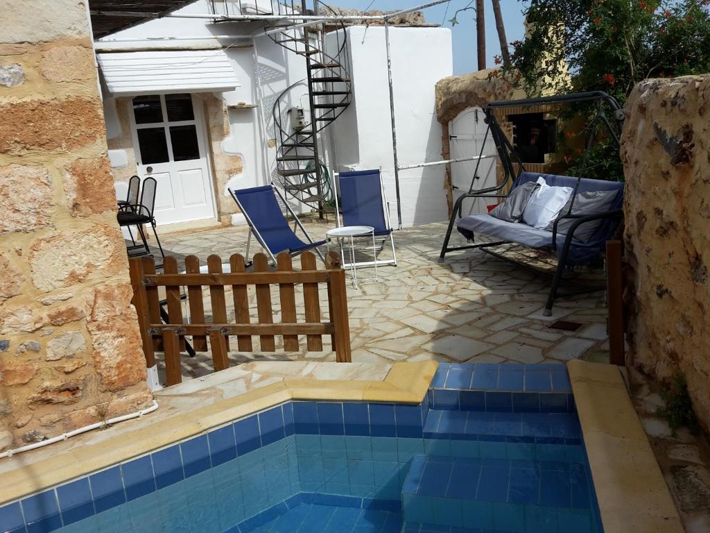 a swimming pool in a yard with chairs and a house at Villa Arismari - Kokkino Chorio in Chania Town