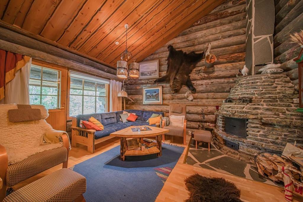 a living room with a stone fireplace in a log cabin at Lapland Cabin Levi in Kittilä