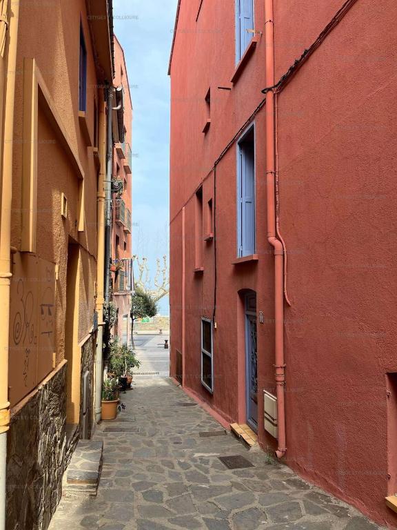 une allée entre deux bâtiments aux murs rouges dans l'établissement 3LIB7 - au cœur du faubourg de Collioure appartement pour 3 personnes, à Collioure