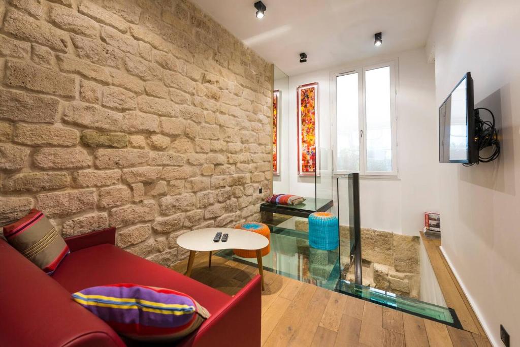 - un salon avec un canapé rouge et un mur en pierre dans l'établissement Le Marais - Place des Vosges - Tournelles 86, à Paris