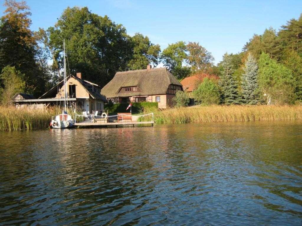 a house on the shore of a lake with a boat at Fischerhaus Whg Sonnenaufgang in Neukloster