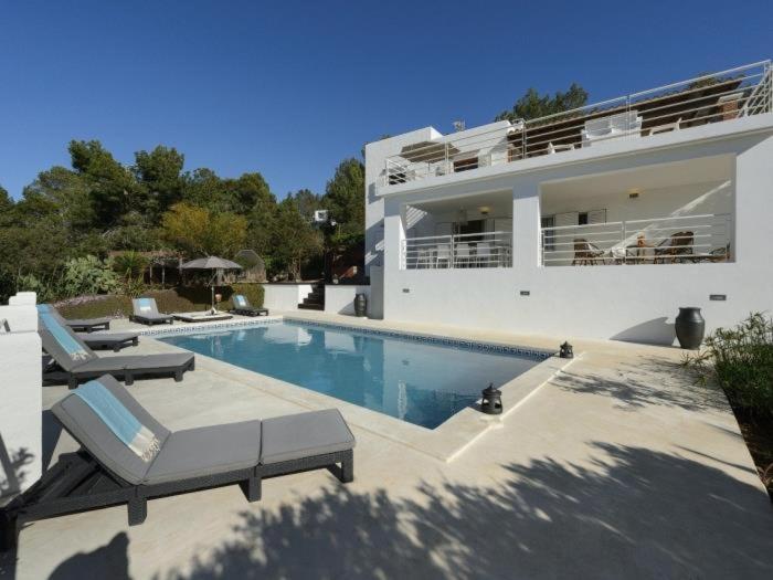 a large house with a swimming pool next to a building at Villa with pool and sea views in Sant Josep de Sa Talaia